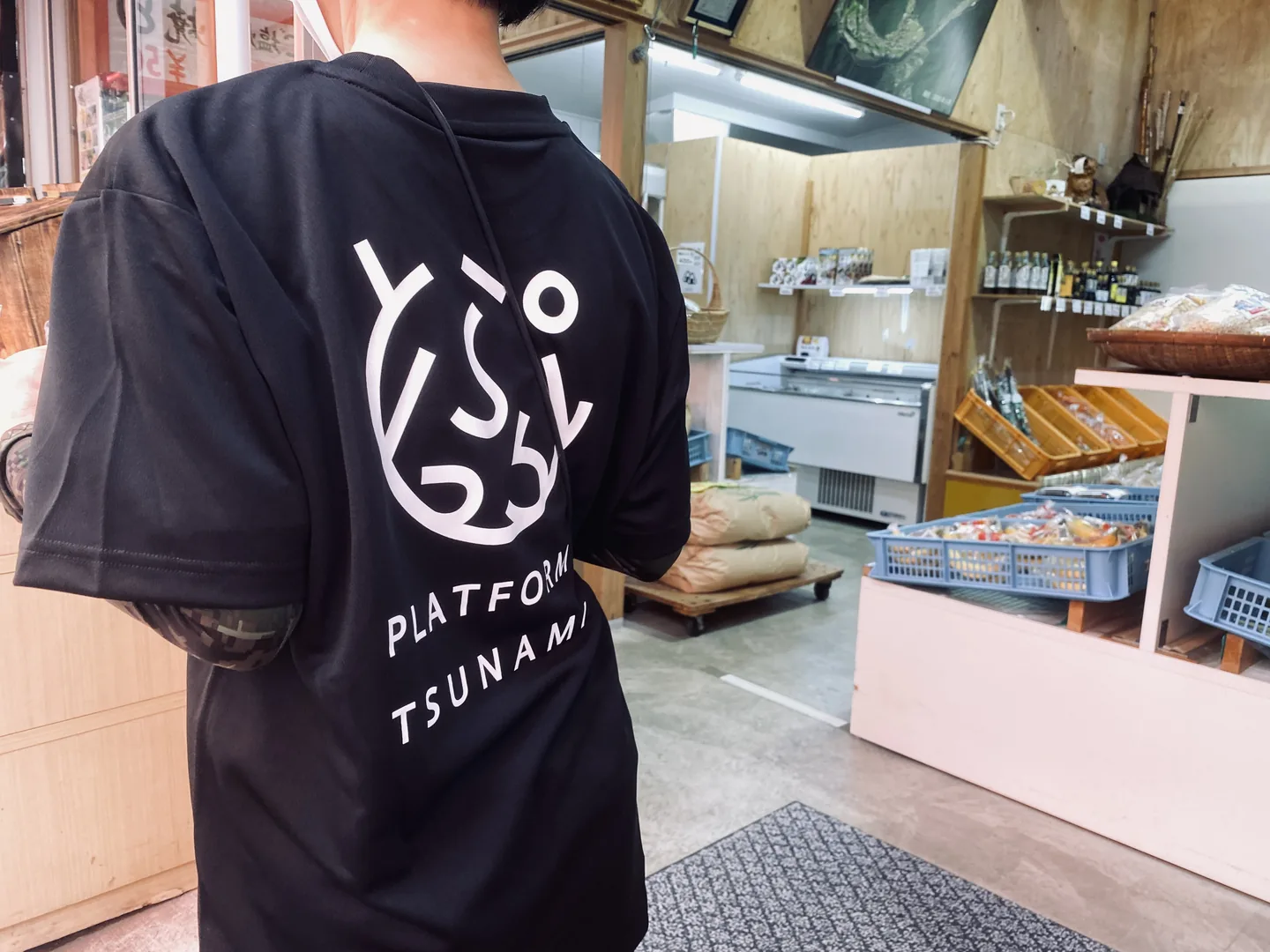 店内でPLATFORM TSUNAMIのロゴ入りTシャツを着用するスタッフの後ろ姿